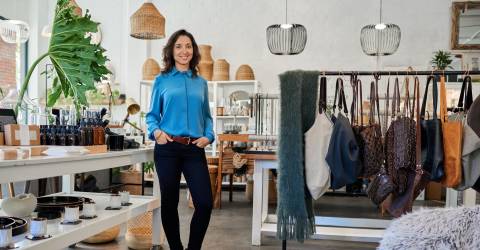 Vrolijke jonge ondernemer in haar eigen trendy winkel